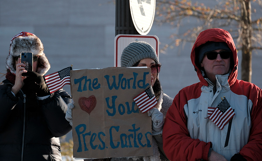 A woman holds up a sign that says the world loves President Carter.