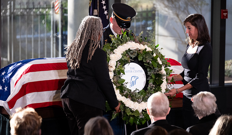 Carter Center CEO Paige Alexander (right) and Jimmy Carter Presidential Library and Museum Director Meredith Evans lay a wreath before the casket.