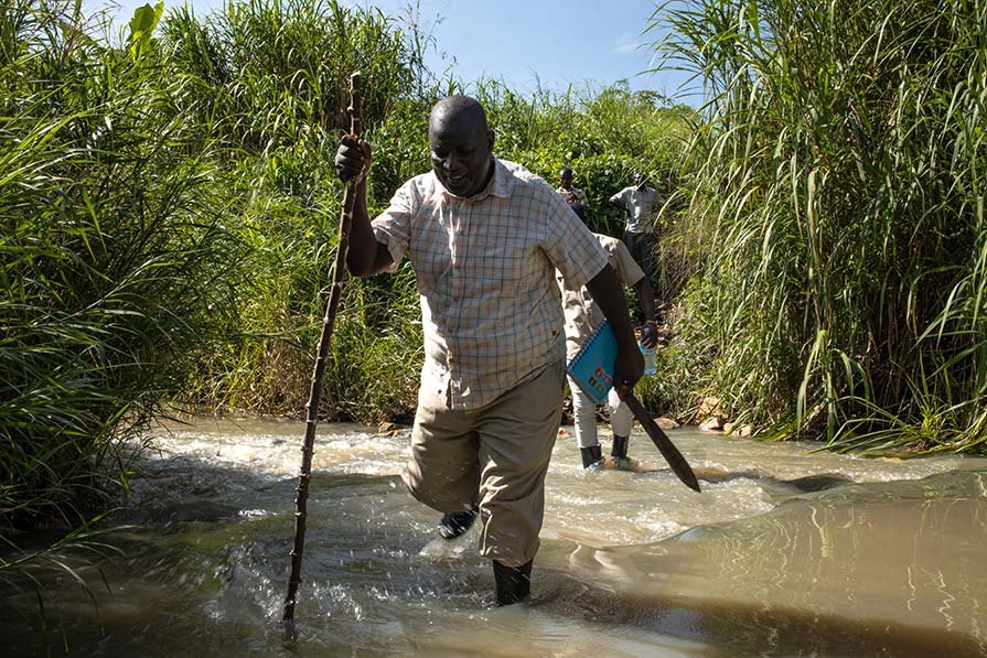 Alex crosses a river using a walking stick